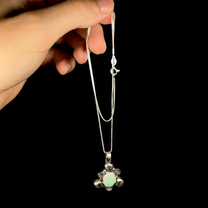 A men's rustic two-tone sterling silver and gold Australian opal necklace, dangled by a hand from its chain.