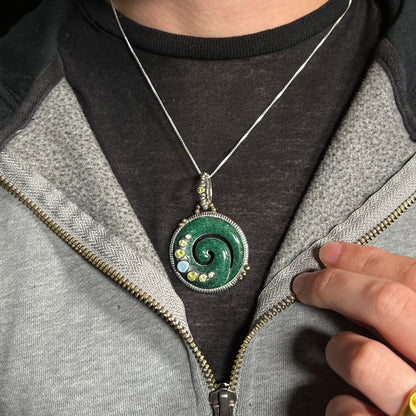 A men's aventurine koru spiral necklace with peridot and opal accents, worn around a neck against a dark shirt.
