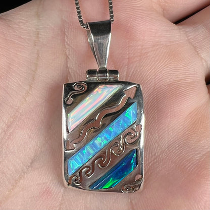 Close-up of a men's 950 silver lab-created opal necklace shown in a hand.