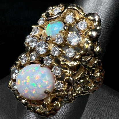 Angled close-up of 1970s brutalist style men's bird's nest ring set with lab-created opals and CZ stones, shown on ring display.