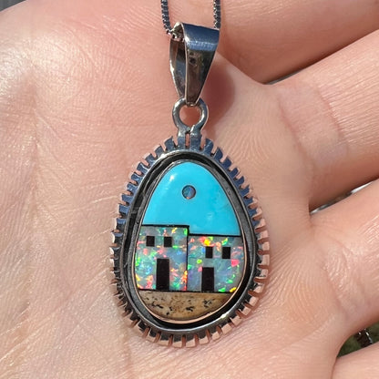A men's Southwest-style silver opal and turquoise inlay necklace shown close-up in a hand in sunlight.