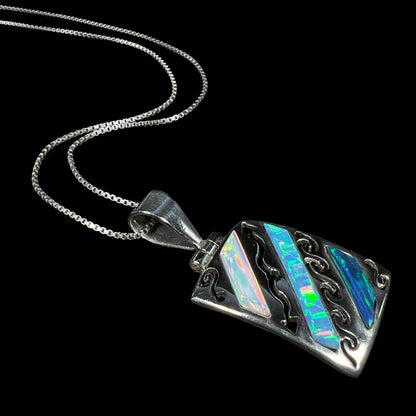 A men's 950 silver lab-created opal necklace shown at an editorial angle, laying on a black background.