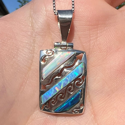 Close-up of a men's 950 silver lab-created opal necklace, shown in the sunlight in a hand.