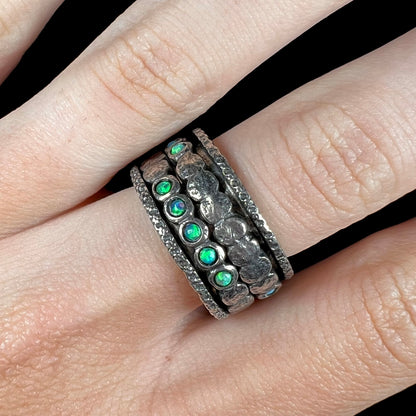 Close-up of finger wearing a men's opal ring.  The opals are round with green play of color.