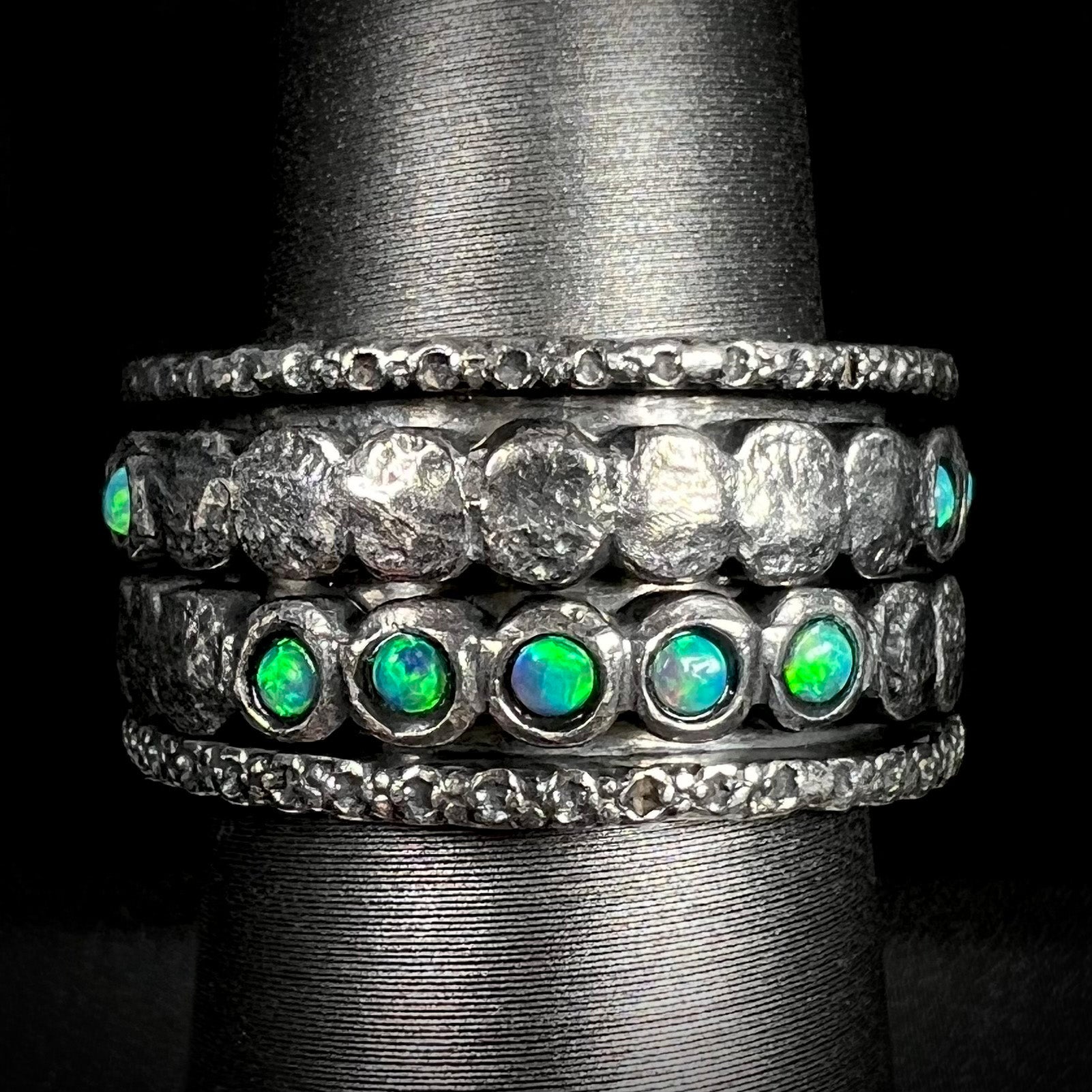 Men's ssilver opal spinner ring that measures 11.5mm wide, shown from the front against black background.
