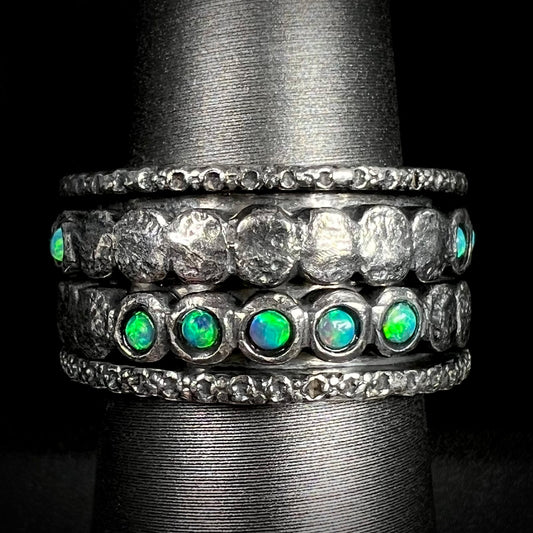 Men's ssilver opal spinner ring that measures 11.5mm wide, shown from the front against black background.