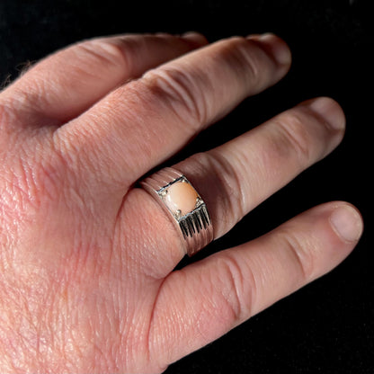 Man's hand wearing a men's sterling silver pink Peruvian opal ring, size 12