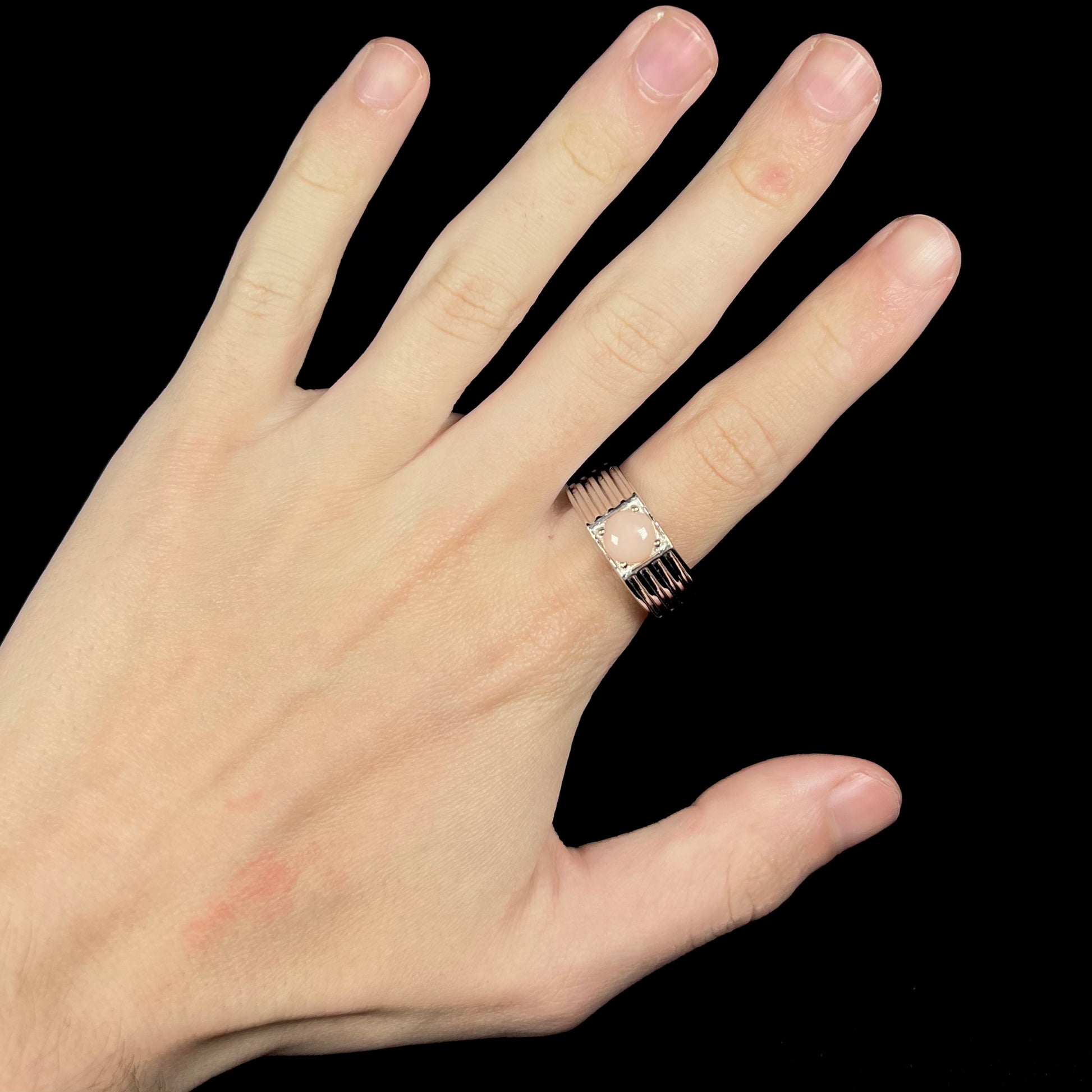Hand wearing men's round pink Pervian opal ring made from sterling silver