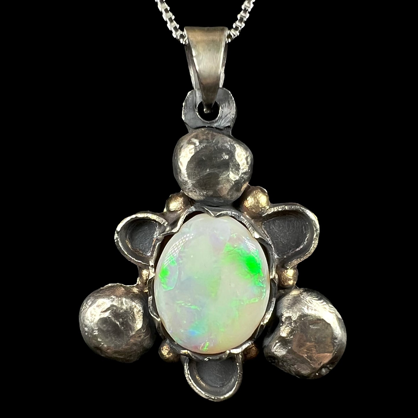 A men's rustic two-tone sterling silver and gold Australian opal pendant, shown close-up against black.