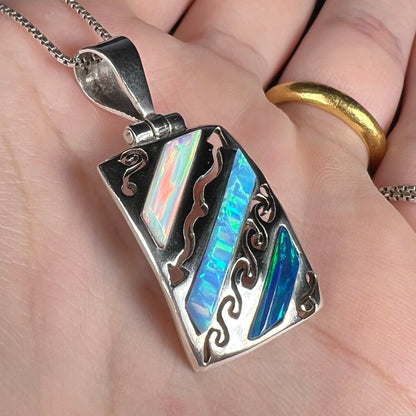 Close-up angled view of a men's 950 silver lab-created opal necklace, shown in a hand.