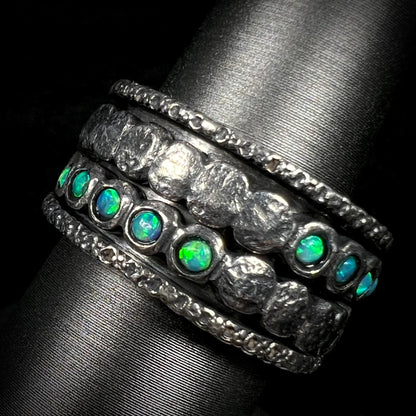 Men's silver opal spinner ring with round, green opals, shown at an angle against a black background.