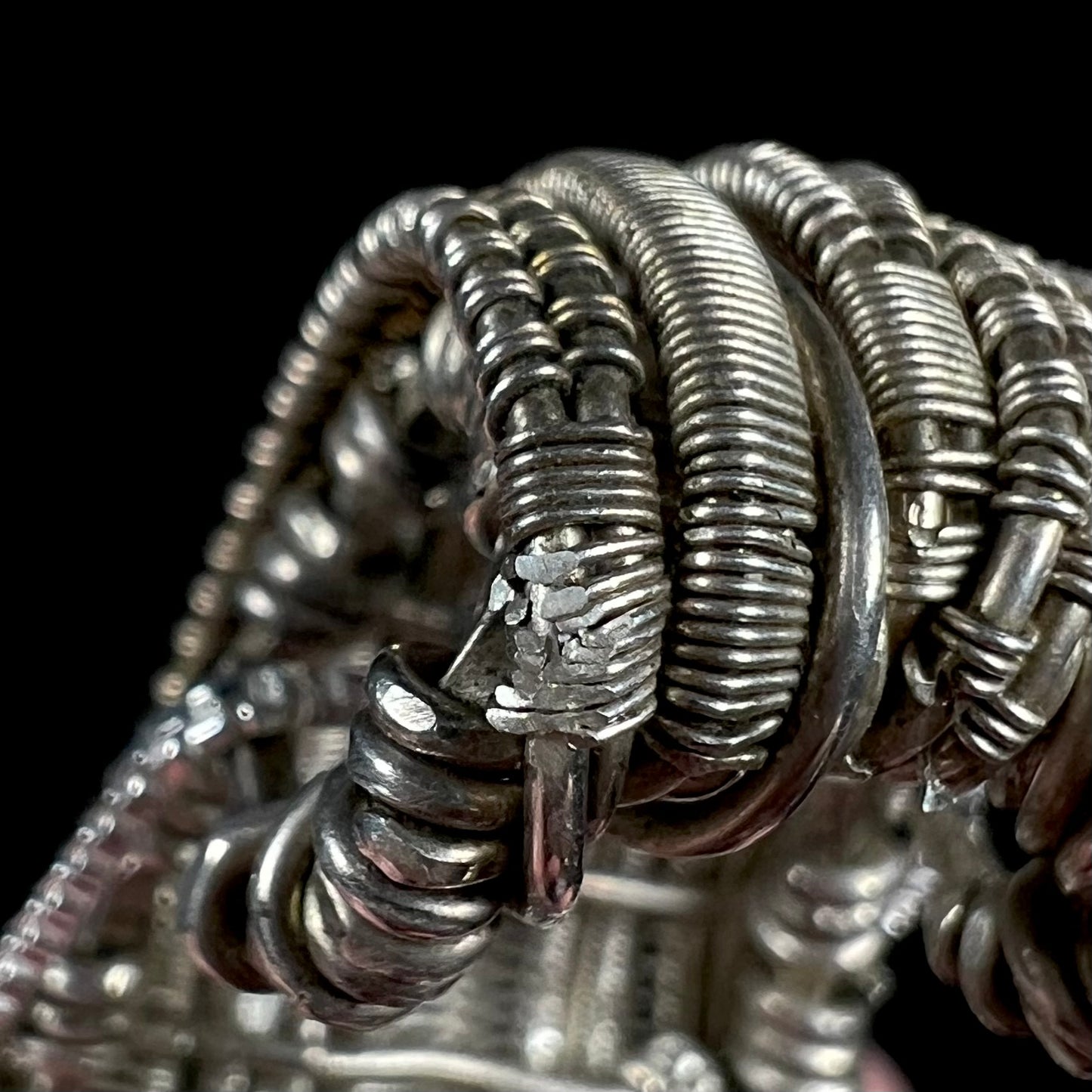 Close-up of silver wire wrapped pendant bail showing damaged wire where design was filed for metal testing.