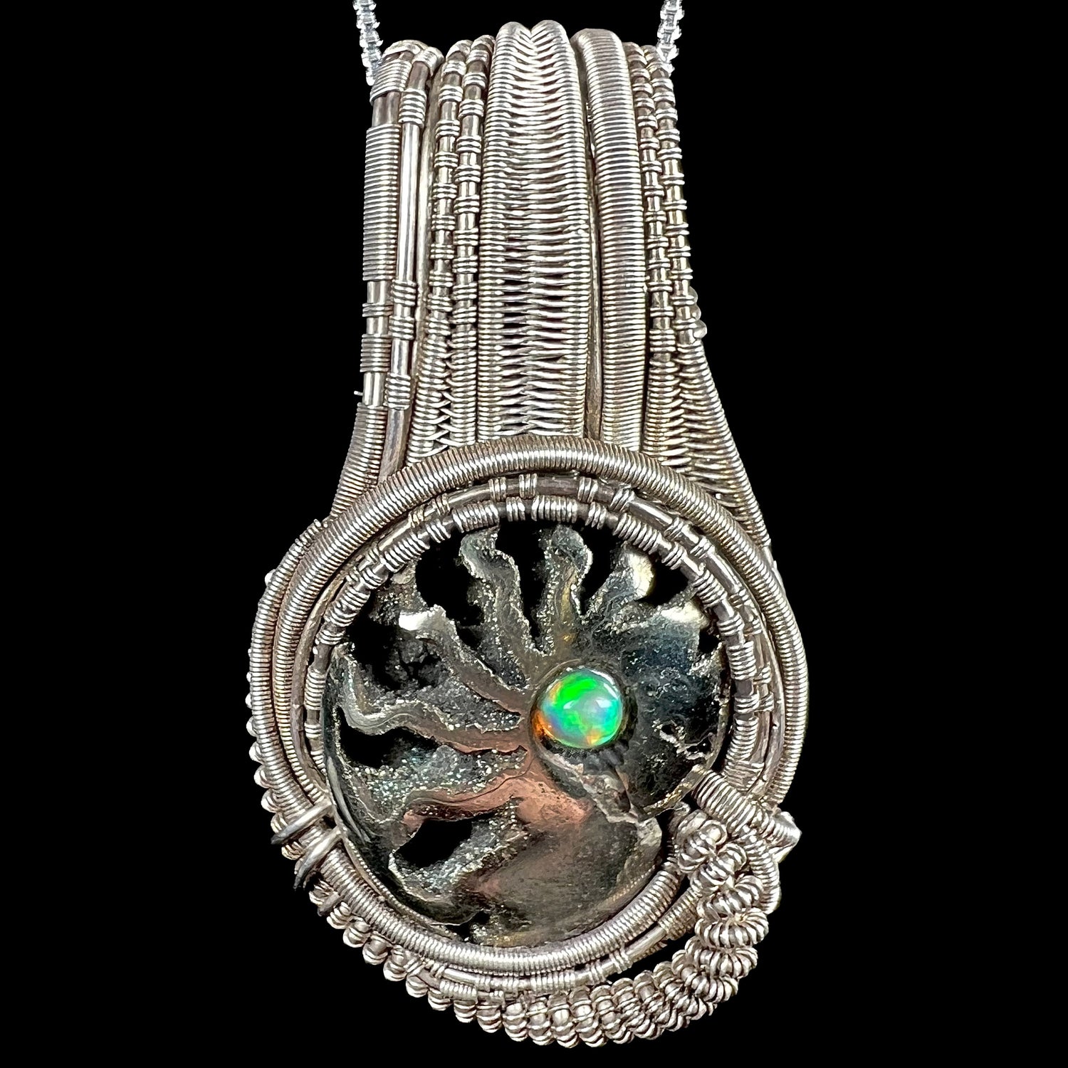 Men's rustic silver wire wrapped pendant set with pyritized ammonite shell fossil, accented by round Ethiopian fire opal, shown from front.