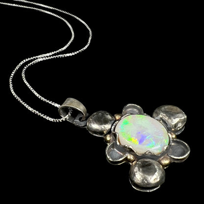 A men's rustic two-tone sterling silver and gold Australian opal necklace, shown from an angle laying on black.