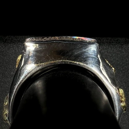 Side gallery profile view of a men's sterling silver ring on a ring display with four gold nugget accents visible.