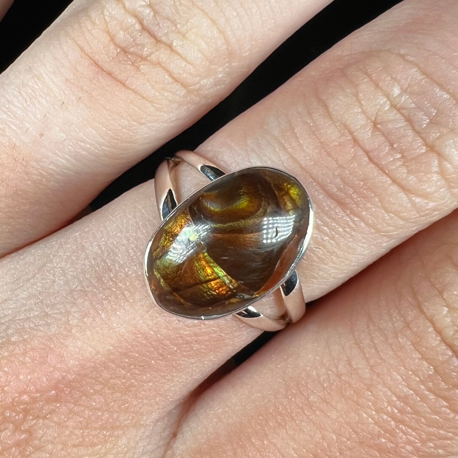 Close-up of a sterling silver Mexican fire agate ring with a split shank worn on a finger.