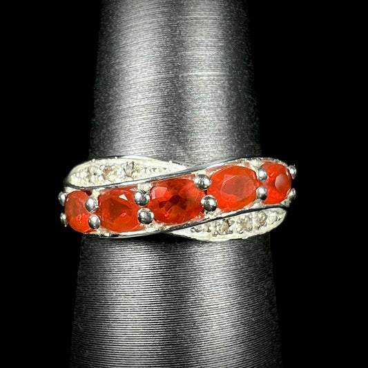 Macro front view of silver Mexican fire opal and diamond ring against a black background.