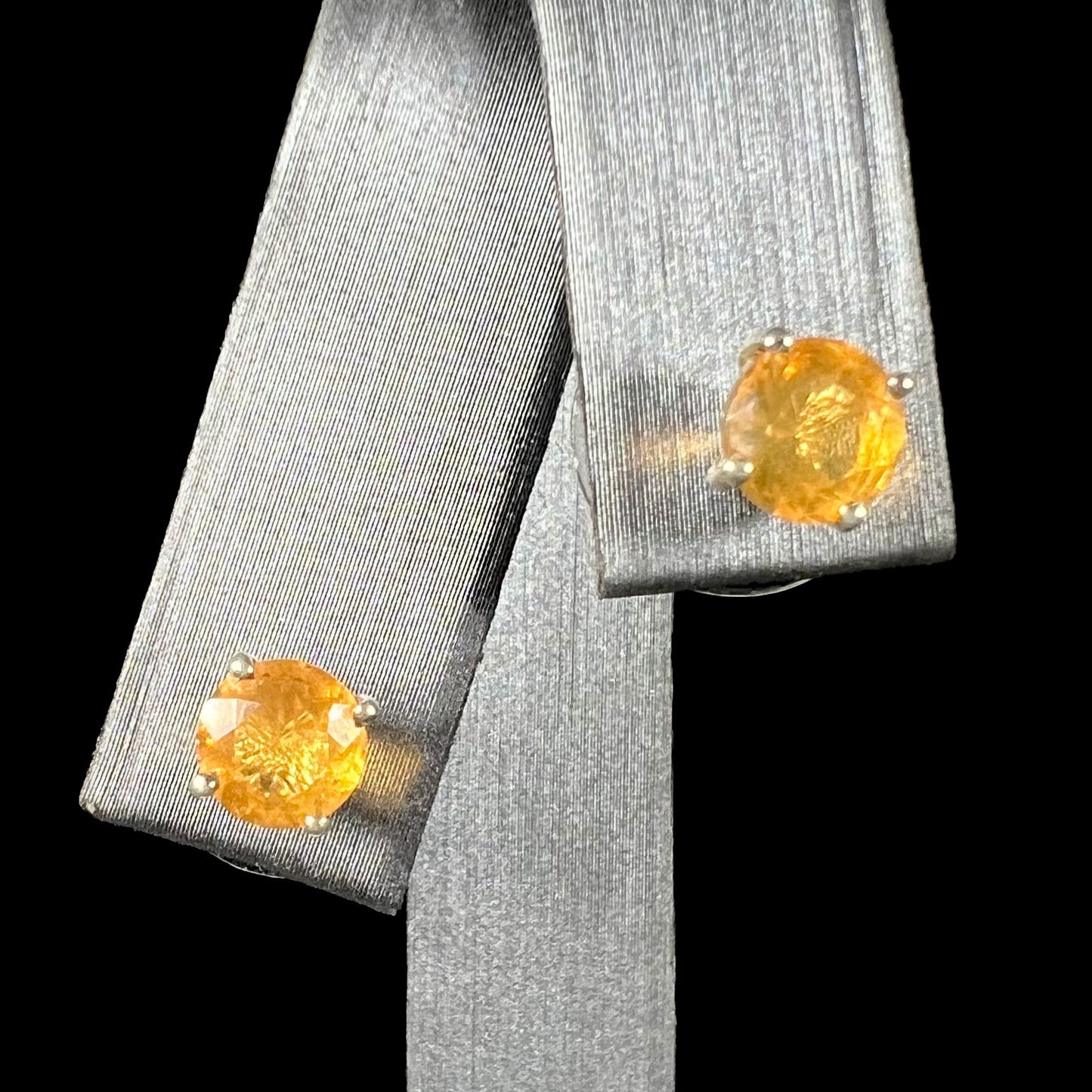 A pair of Mexican fire opal stud earrings in sterling silver shown from the front against a black background.