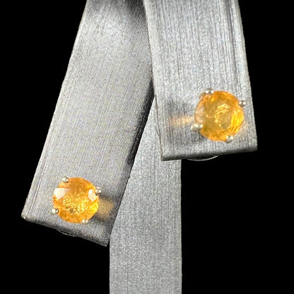 A pair of Mexican fire opal stud earrings in sterling silver shown from the front against a black background.
