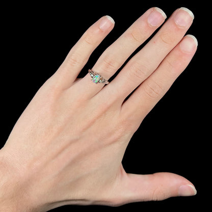 A platinum Mexican jelly opal engagement ring on a hand.  The ring has diamond accents.