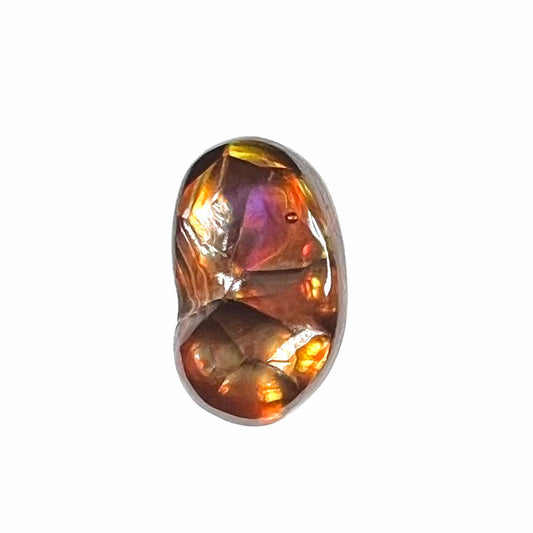 A loose Mexican fire agate gemstone.  The stone is red with a puddle of purple and exhibits a metallic luster.