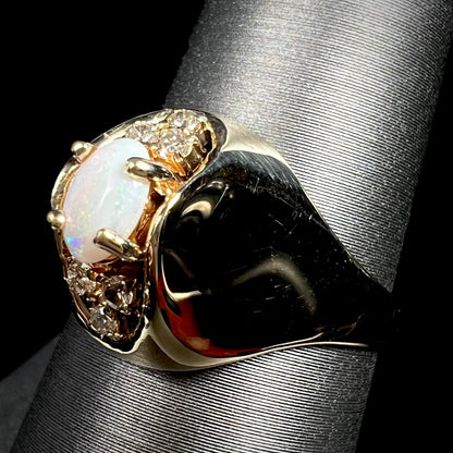 Angled macro view of Mid-Century era 14k gold opal and diamond ring with a highly polished dome design, shown on ring display