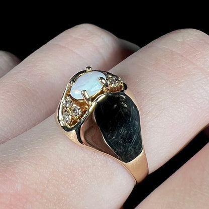 Close-up angled view of Mid-Century modern opal and diamond ring with high-profile 14k gold domed design, worn on finger