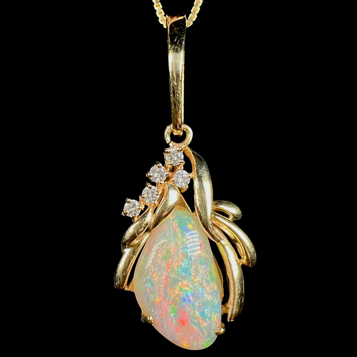 Close-up of Modernist-style 14k yellow gold Coober Pedy shell opal pendant with diamond accents, shown from the front against black background.