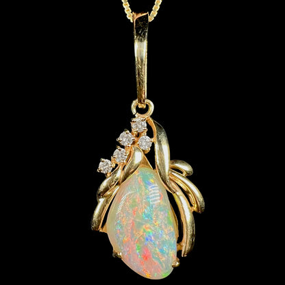 Close-up of Modernist-style 14k yellow gold Coober Pedy shell opal pendant with diamond accents, shown from the front against black background.