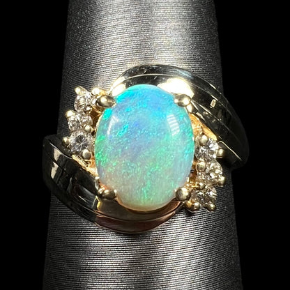 Close-up of 1980s Modernist style 14k gold crystal opal and diamond ring with bypass shank design, on ring display