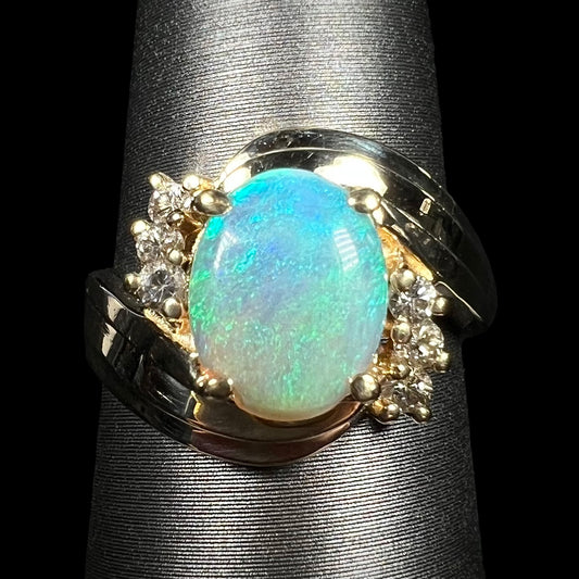 Close-up of 1980s Modernist style 14k gold crystal opal and diamond ring with bypass shank design, on ring display