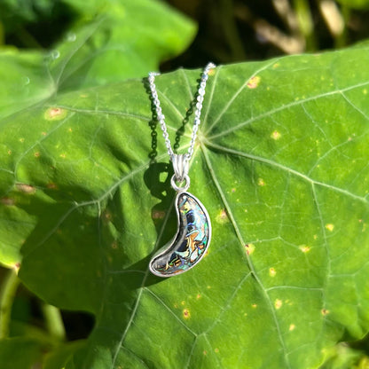 A sterling silver necklace set with a natural Koroit boulder opal shaped like a crescent moon.