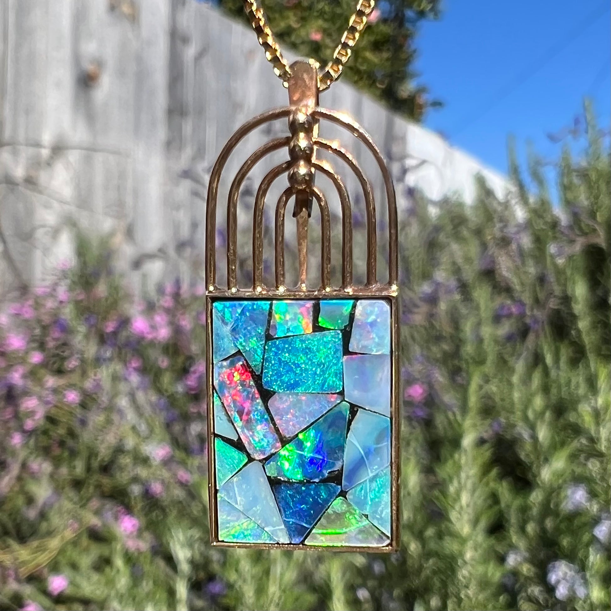 Macro shot of a mosaic opal necklace in sunlight, showing vibrant colors and visible crazing on the opal surface.