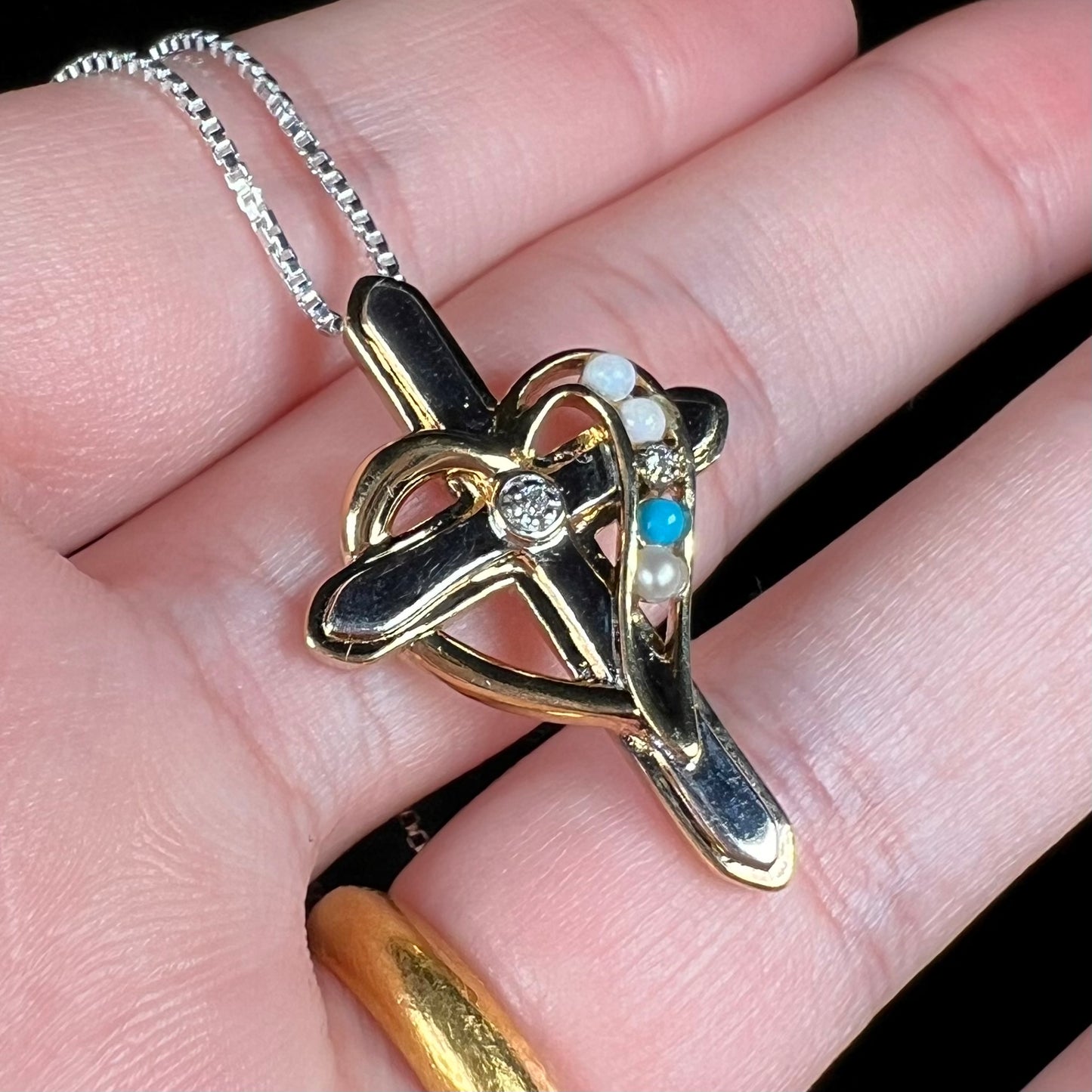 A two-tone sterling silver mother's cross necklace set with diamond, opal, turquoise, and pearl.