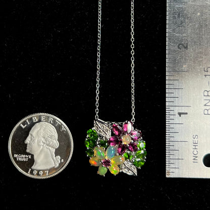 A multi-gemstone flower necklace shown next to a quarter coin and ruler.