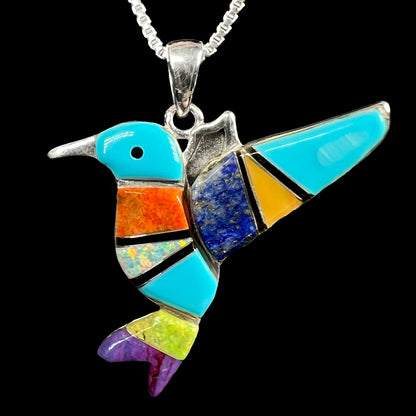 A multi-stone turquoise & opal inlay hummingbird necklace in sterling silver, shown against a black background.