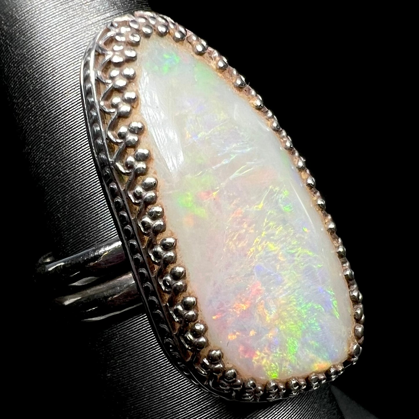 Angled close-up view of natural Australian opal ring with multicolor fire and a sterling silver crown-design setting.
