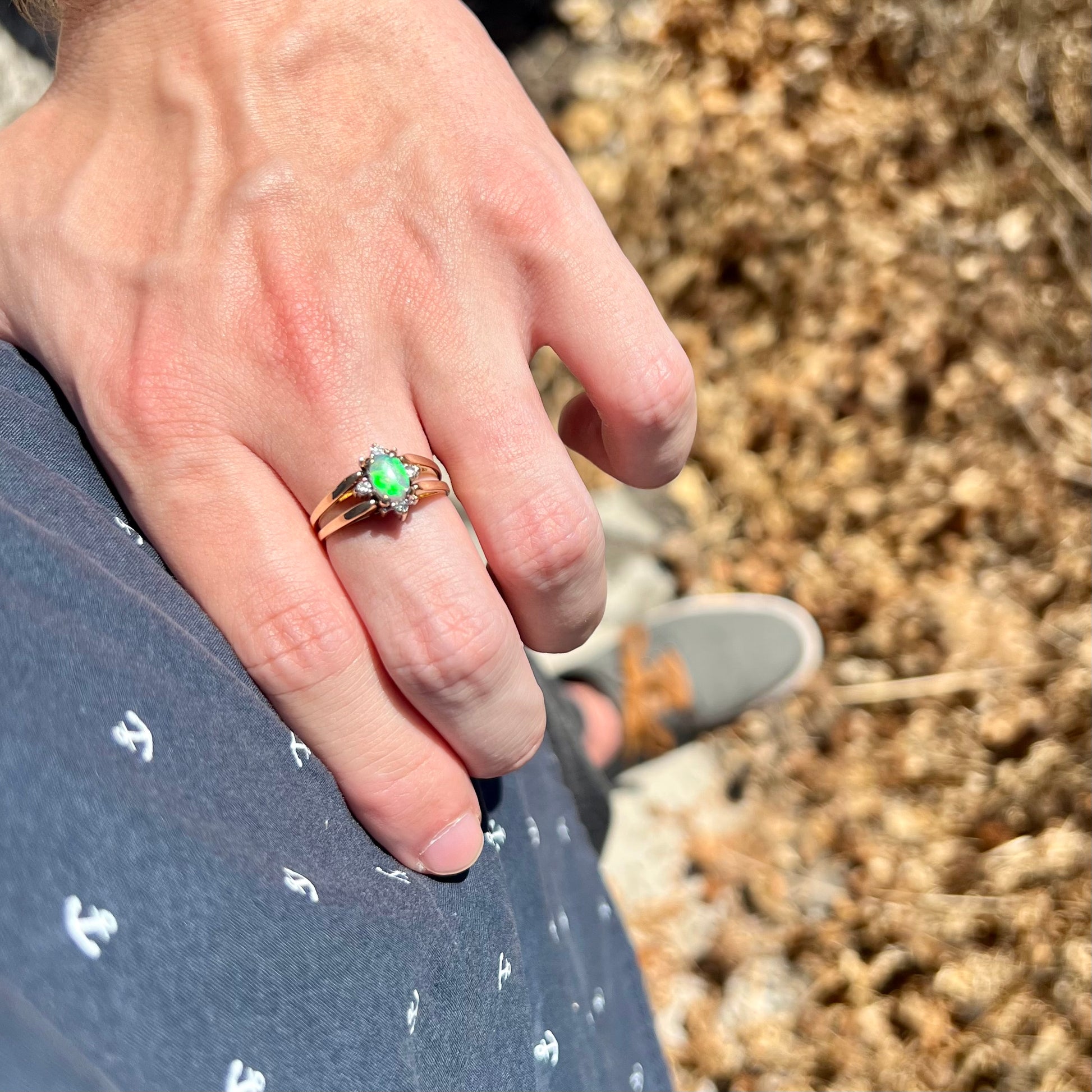 Hand resting on person's hip in sunlight wearing natural green Australian opal and diamond ring in 14k gold