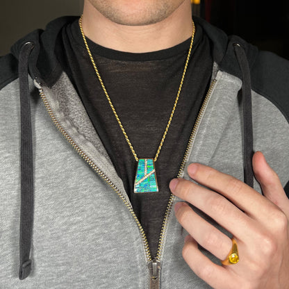 Man wearing a natural opal inlay necklace around his neck inside of a partially unzipped hoodie against a dark shirt.