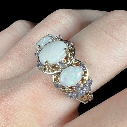 Angled macro close-up of a natural Australian opal ring made from sterling silver with tanzanite accents, worn on a finger.