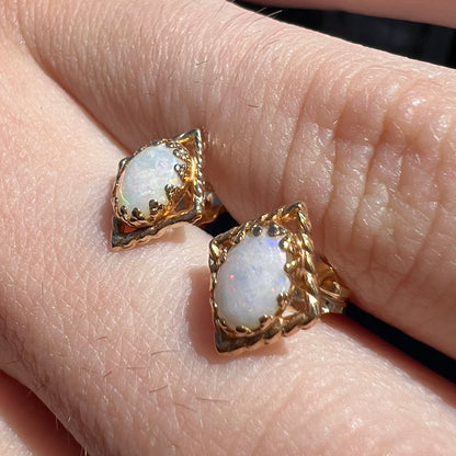 A pair of opal stud earrings.  The opals are set in yellow gold diamond shaped mountings.