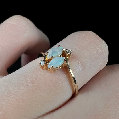 A ladies' gold ring mounted with two marquise cut opals and two diamond accents.
