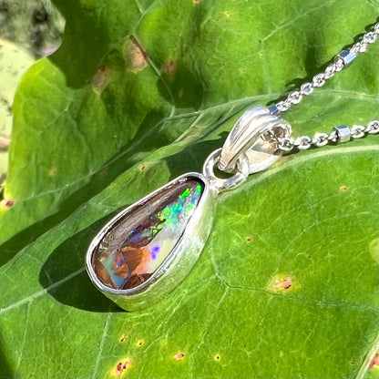 A pear shaped boulder opal necklace in sterling silver.  The opal has bright green and blue flashes.