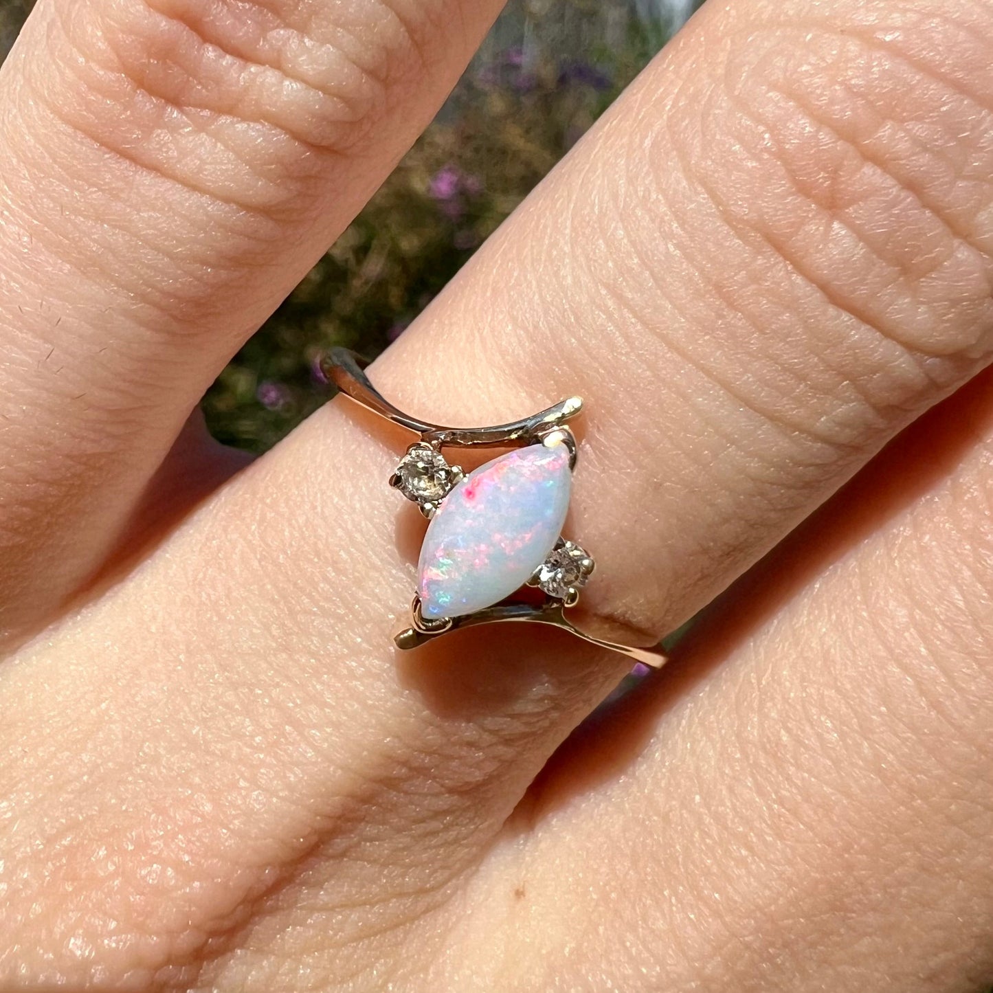 A yellow gold marquise cut opal ring set with two white sapphire accent stones.