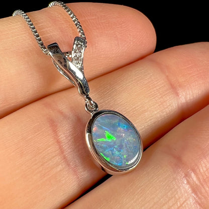 A sterling silver necklace set with a natural black opal doublet and white zircon accent stones.