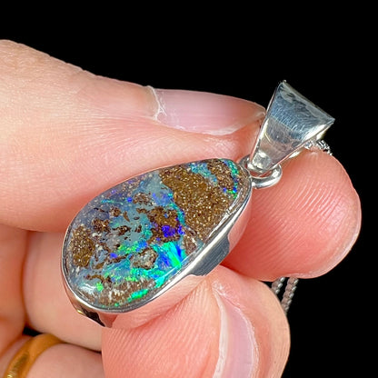 A sterling silver pendant set with an Australian boulder opal on a silver box chain.