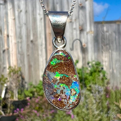 A sterling silver necklace set with a rainbow boulder opal stone.