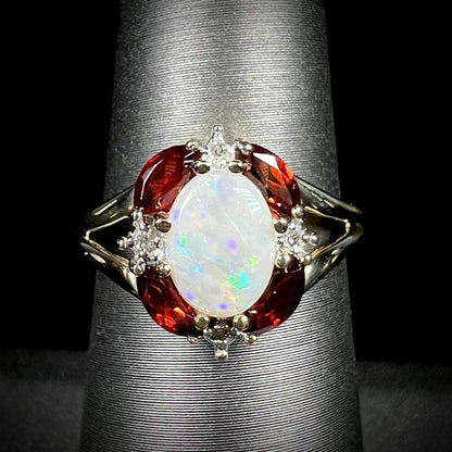 A ladies natural opal ring in yellow gold.  The opal is surrounded by red marquise cut garnets and diamonds.