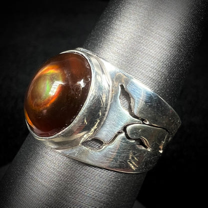 A silver fire agate ring with a nature-inspired open vine and flower design along the band, shown at an angle.