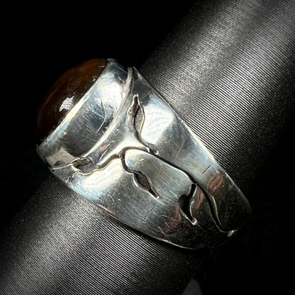 A sterling silver ring with an open nature-inspired vine motif in the design, shown from the side.